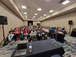 full room of participants at conference session