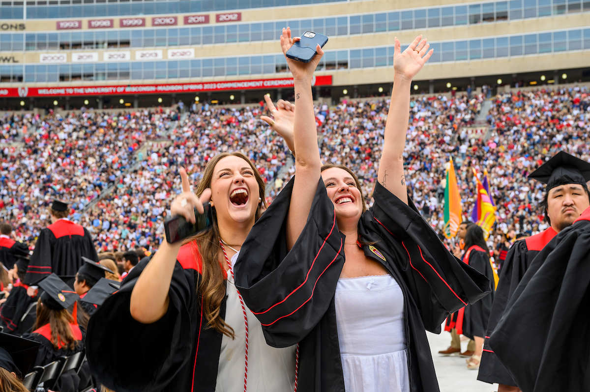 Two people celebrating at UW commencement with their hands in the air
