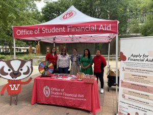 5 people stand next to a cardboard cutout of Buddy Bucky under a tent and behind a table both branded with Office of Student Financial Aid.