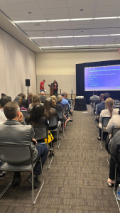 An audience watches a presentation in an exhibition hall.