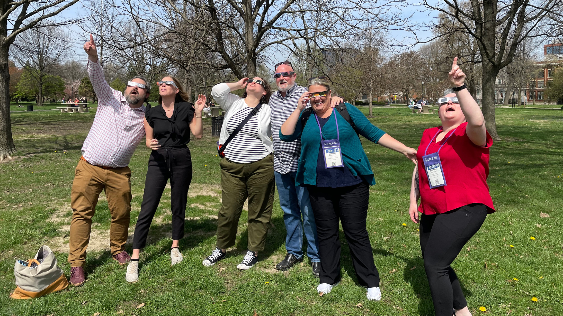 Six people look up at a solar eclipse visible in the sky.