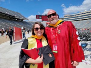 Two people pose for a picture in academic regalia