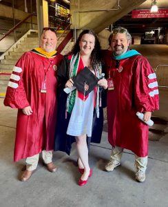 Three people pose for a picture in academic regalia