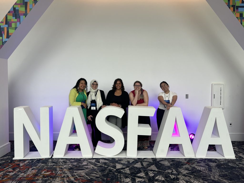 A group of women stand behind tall letters that spell NASFAA