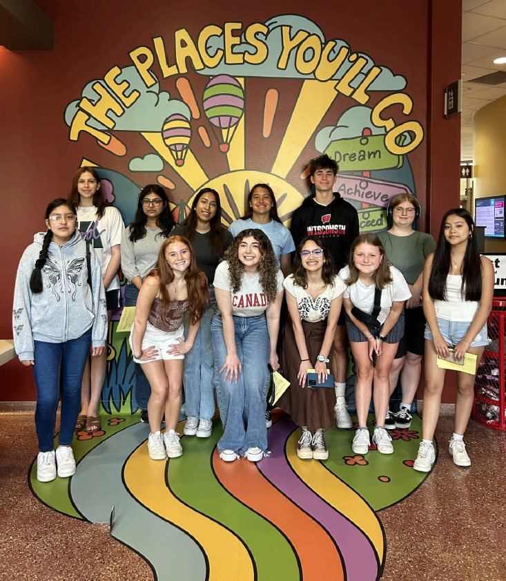 Group of students stand in front of a mural that says "The places you'll go."