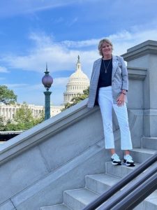 A woman stands on steps with the U.S. Capitol in the background
