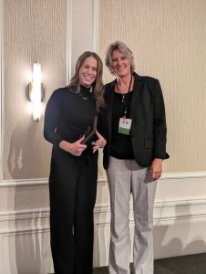 Two women pose for a picture in an event space.