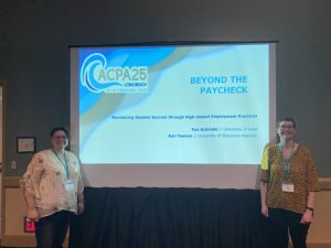 Two women stand in front of a presentation screen.
