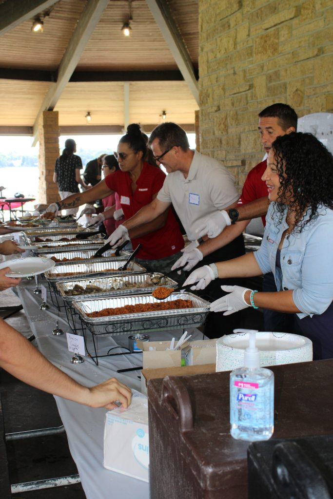 People serving food at a buffet table during a community event.