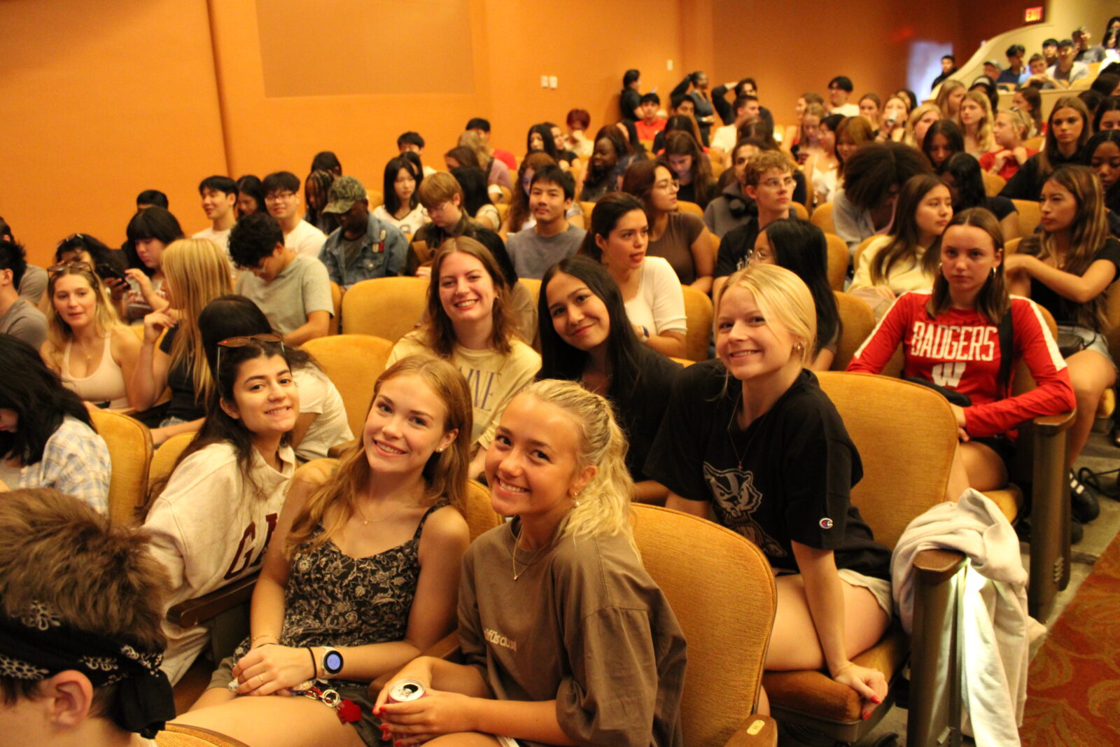 A group of students smile for the camera while seated in the theatre.