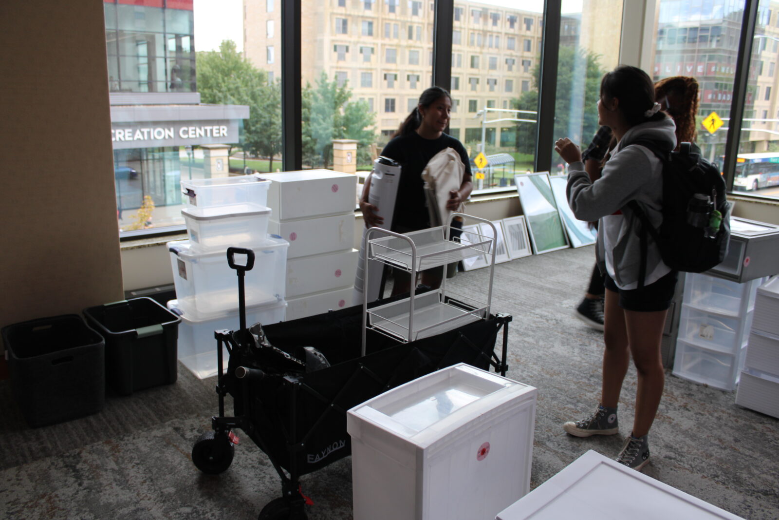 A student puts items in the wheeled cart she brought along.