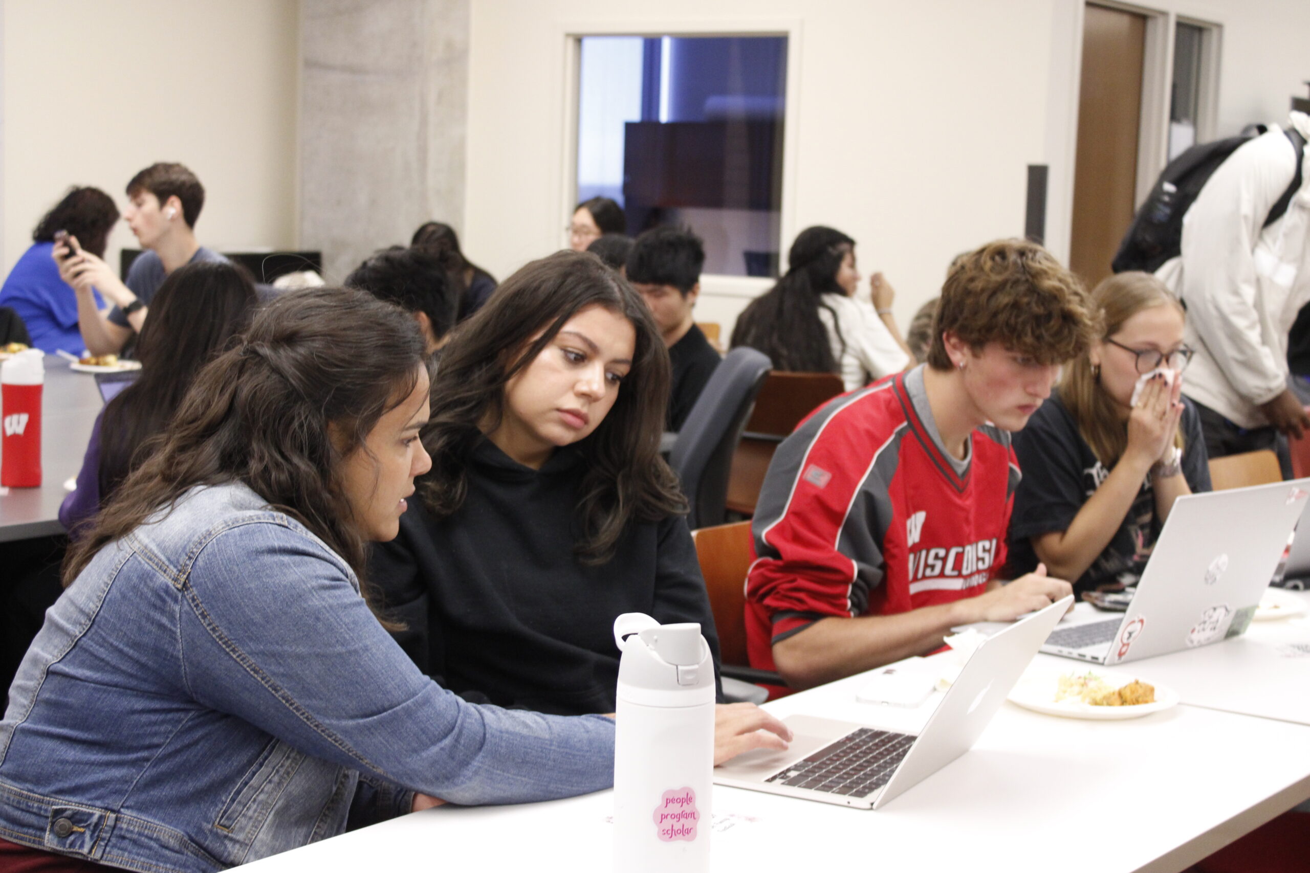 An advisor sits next to a student completing the FAFSA on her laptop.